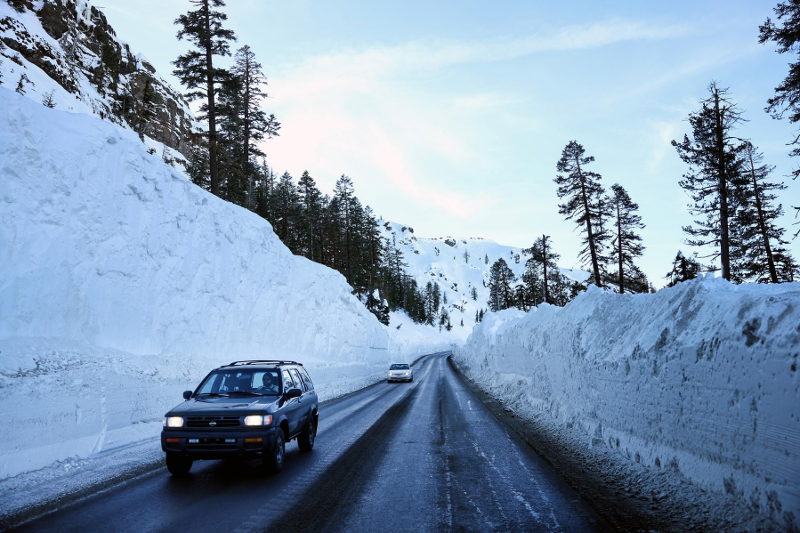 Vehicles pass along a highway snowplowed through deep snow after a series of atmospheric river storms on Jan. 21, 2023, near Kirkwood, California.