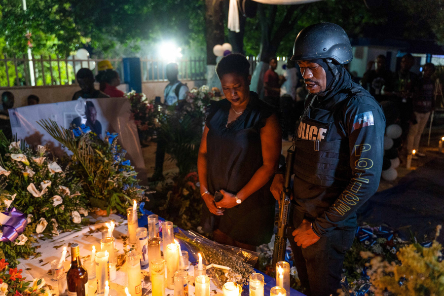 A woman and a police officer pay their respects during a vigil in memory of three police officers killed by armed gangs, Jan. 30, 2023, in Petion-Ville, Port-au-Prince, Haiti.
