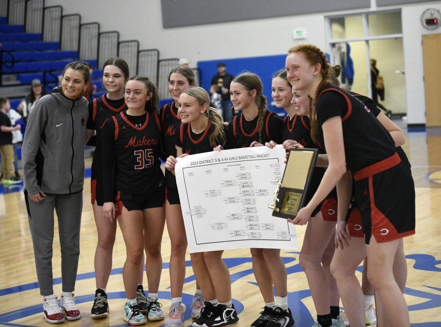 The Camas girls basketball team poses with the championship trophy and tournament bracket after winning the 4A bi-district girls basketball championship at Curtis High School in University Place on Saturday, Feb. 18, 2023.