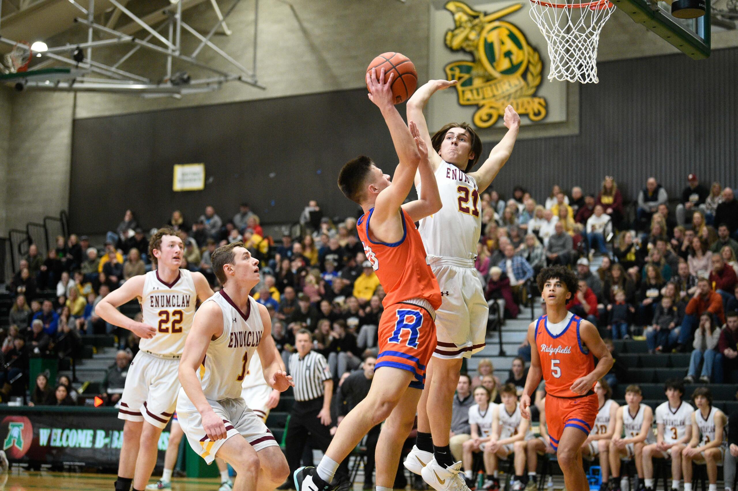 Enumclaw's Karson Holt (21) contests a shot attempt from Ridgefield's Carter Thompson in a Class 2A state opening round game on Saturday, Feb. 25, 2023, at Auburn High School.