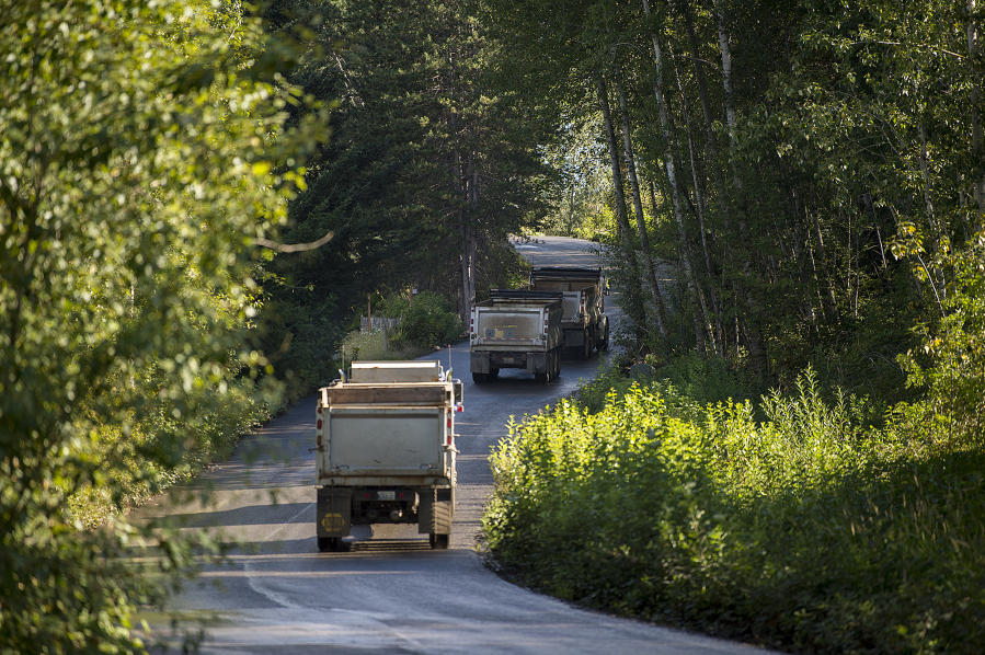 Trucks drive toward the Zimmerly gravel pit east of Washougal in July 2018. Operators of the pit, long the subject of opposition from neighbors and conservation groups, are seeking permission to keep extracting gravel from the site.