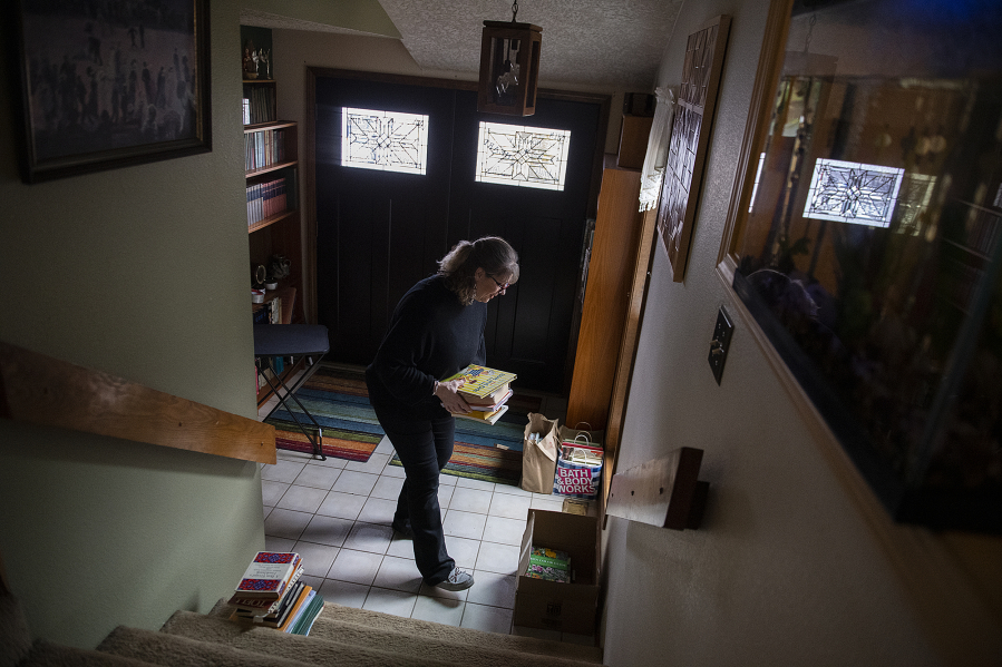Retired educator Lisa Emmerich sorts through her collection of books to decide which she will take when she and her husband relocate from the Vancouver area to Santa Fe, N.M.