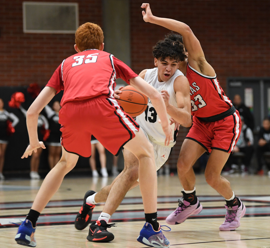 Union senior Yanni Fassilis, center, drives between two Camas defenders Friday, Feb. 3, 2023, during the first half of a game between Camas and Union at Union High School.