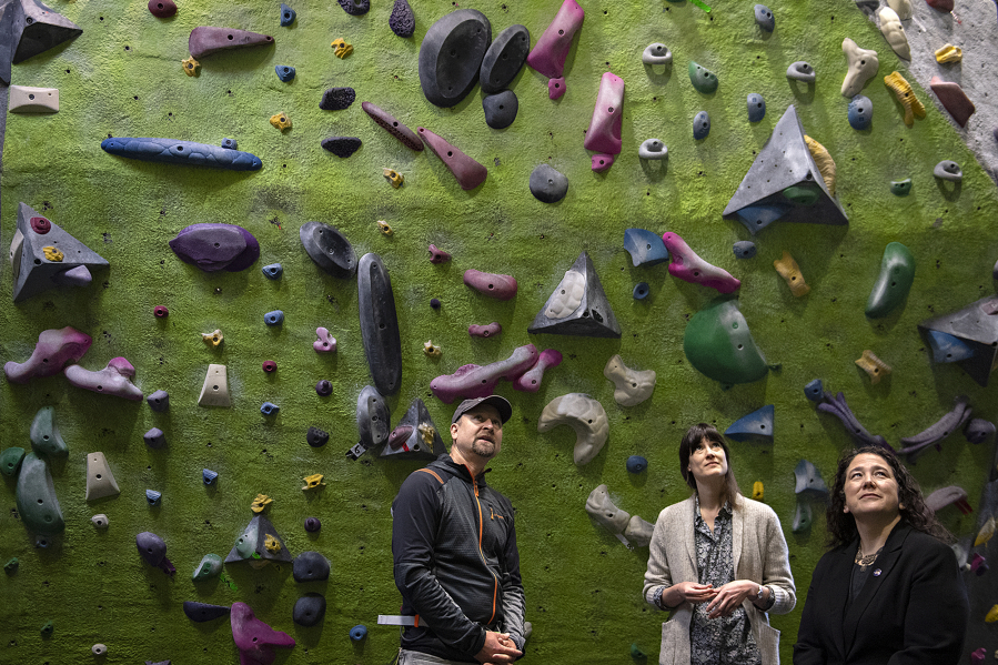 From left: Hanz Kroesen, co-owner of Source Climbing Center, looks up at the climbing wall with U.S. Rep. Marie Gluesenkamp Perez, D-Skamania, and Isabel Guzman, head of the Small Business Administration, during a tour Friday morning.