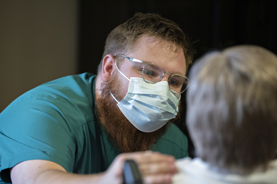 Certified nursing assistant Benjamin Nikolaychuk shares eye contact and a reassuring touch with a resident at The Hampton at Salmon Creek Memory Care Community, using techniques from a new approach to memory care called Humanitude.
