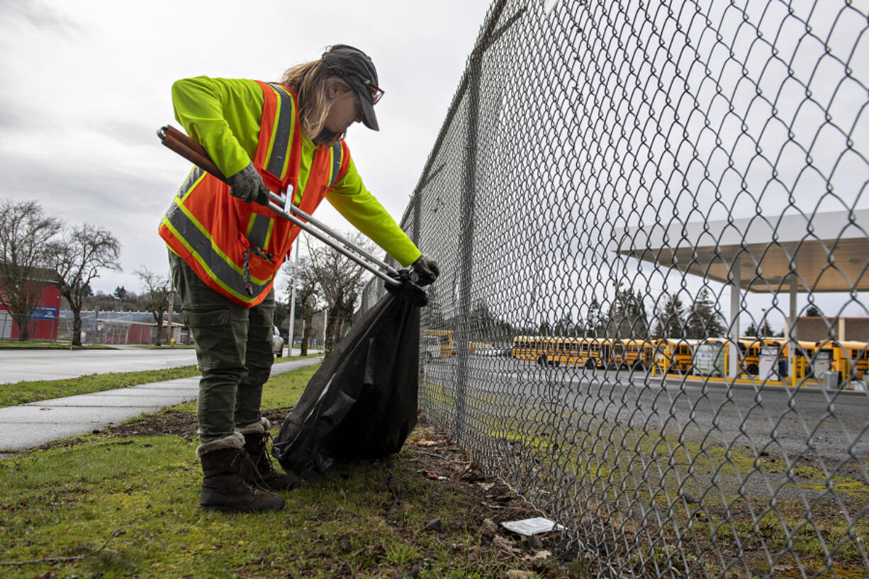 Outpost resident Courtney Ligman, who works in Share's Talkin' Trash program, picks up garbage across from Fort Vancouver High School on a Tuesday afternoon in February.
