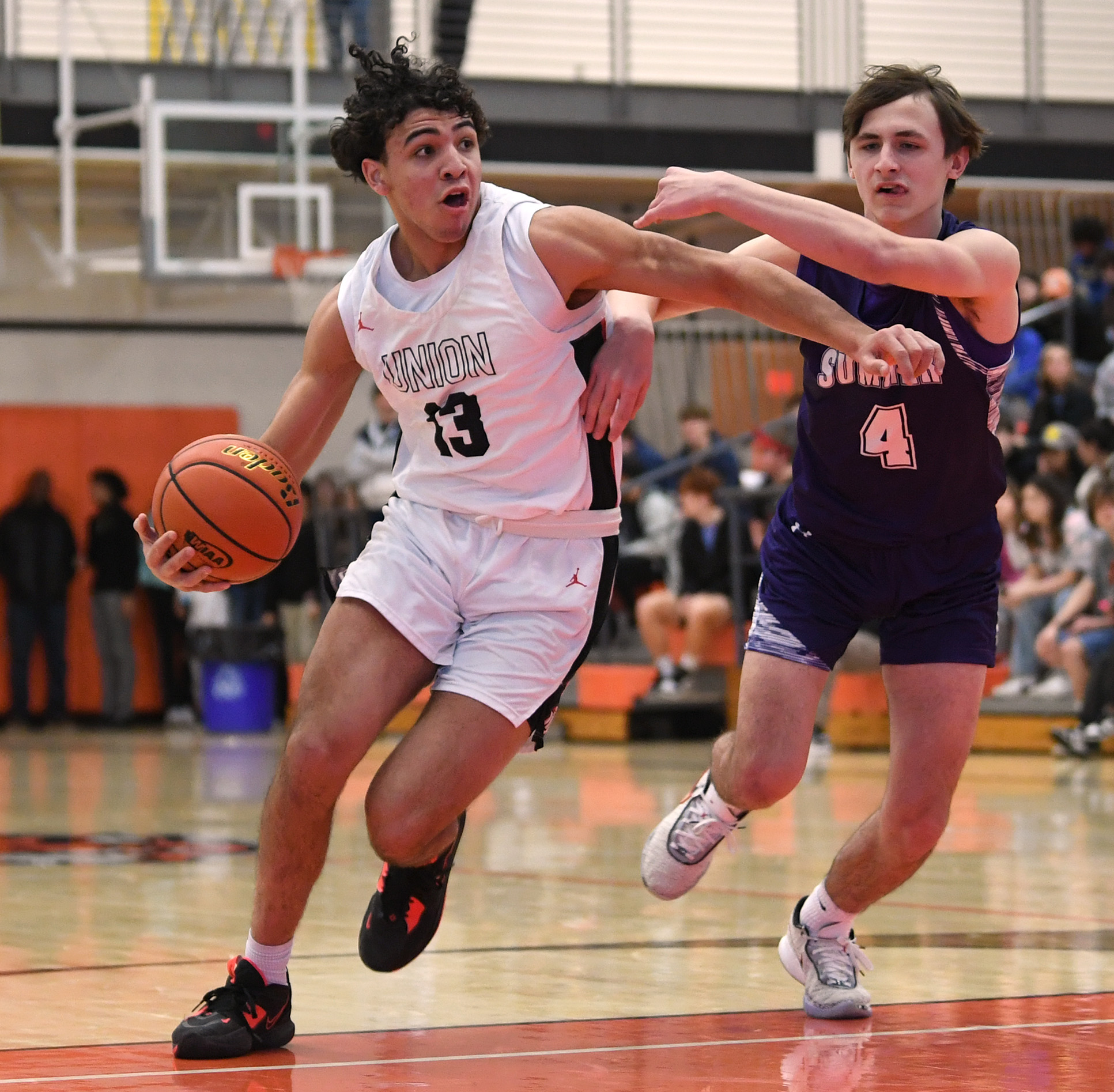 Union senior Yanni Fassilis, left, drives to the basket under pressure from Sumner sophomore Jaylen Hyppa on Saturday, Feb. 25, 2023, during the Titans’ 67-40 at Battle Ground High School.