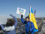Vancouver resident Andrey Shulik, right, and Maria Everhart stand on the Interstate 205 bridge pedestrian path on Saturday afternoon during a weekly rally raising awareness of the war in Ukraine. Saturday marked the 51st weekend that the rally has taken place.