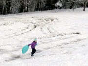 Lily Eakin, 11, of Vancouver runs up a hill with her sleds Thursday morning at Leverich Park in Vancouver.