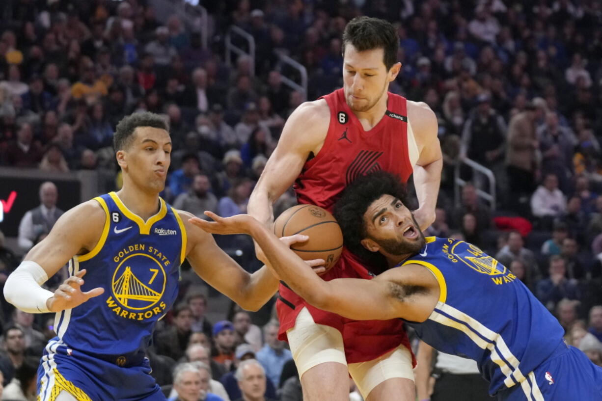 Portland Trail Blazers forward Drew Eubanks, middle, reaches for the ball between Golden State Warriors forward Patrick Baldwin Jr. (7) and forward Anthony Lamb during the first half of an NBA basketball game in San Francisco, Tuesday, Feb. 28, 2023.