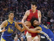Portland Trail Blazers forward Drew Eubanks, middle, reaches for the ball between Golden State Warriors forward Patrick Baldwin Jr. (7) and forward Anthony Lamb during the first half of an NBA basketball game in San Francisco, Tuesday, Feb. 28, 2023.