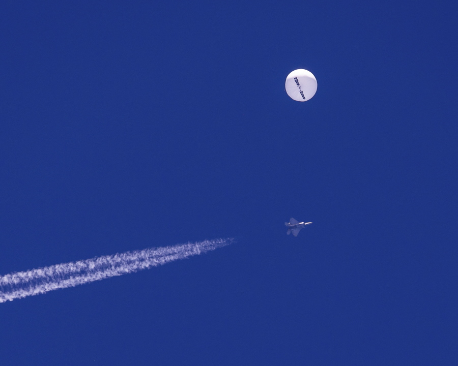 In this photo provided by Chad Fish, a large balloon drifts above the Atlantic Ocean, just off the coast of South Carolina, with a fighter jet and its contrail seen below it, Saturday, Feb. 4, 2023. The balloon was struck by a missile from an F-22 fighter just off Myrtle Beach, fascinating sky-watchers across a populous area known as the Grand Strand for its miles of beaches that draw retirees and vacationers.