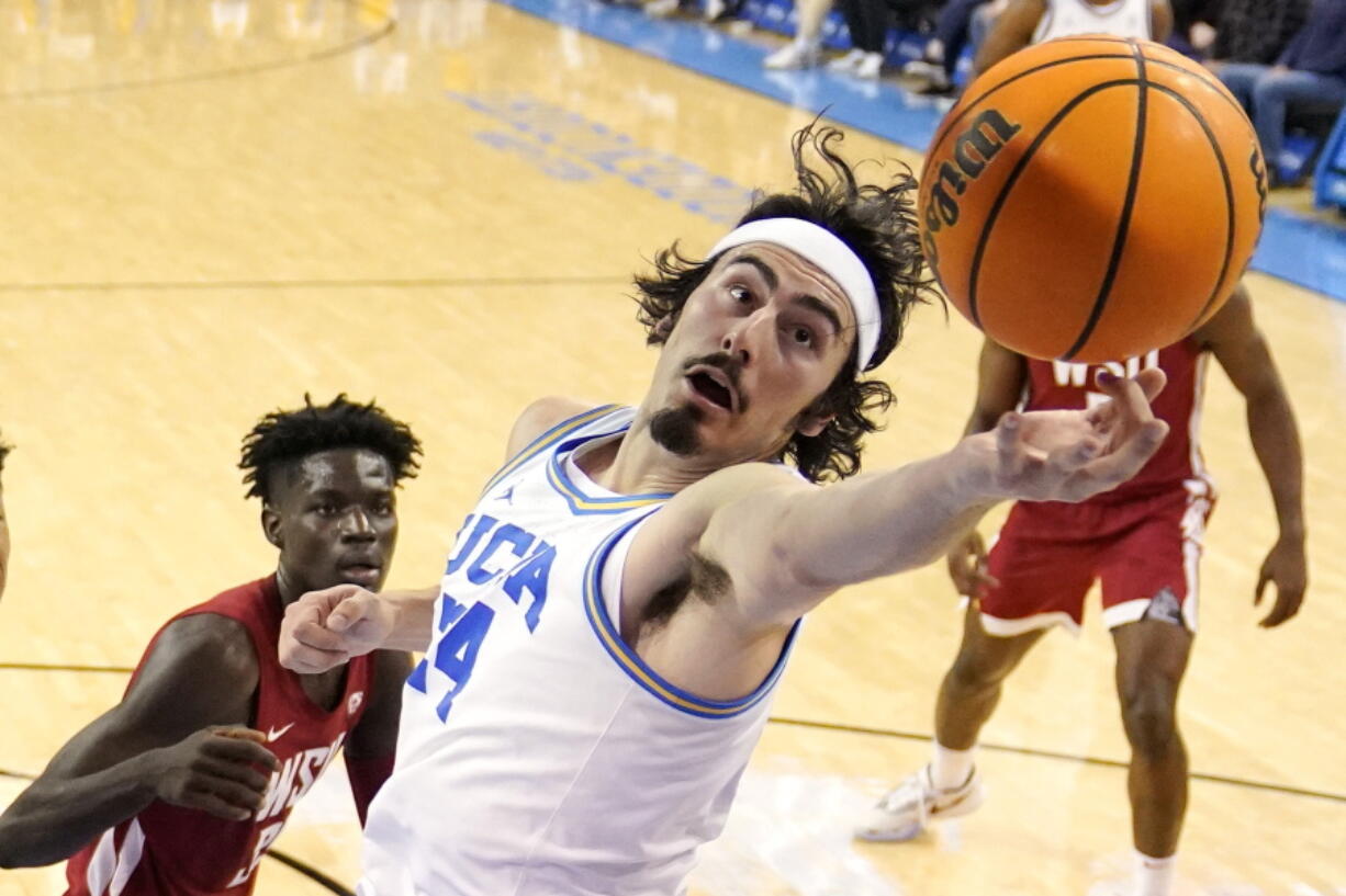 UCLA guard Jaime Jaquez Jr., right, reaches for a rebound as Washington State forward Mouhamed Gueye watches during the first half of an NCAA college basketball game Saturday, Feb. 4, 2023, in Los Angeles. (AP Photo/Mark J.