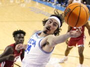 UCLA guard Jaime Jaquez Jr., right, reaches for a rebound as Washington State forward Mouhamed Gueye watches during the first half of an NCAA college basketball game Saturday, Feb. 4, 2023, in Los Angeles. (AP Photo/Mark J.