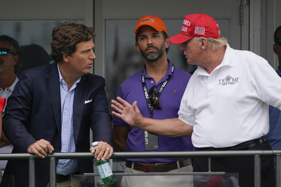 FILE - Former President Donald Trump, right, talks with Donald Trump Jr., center, and Tucker Carlson at the 16th tee during the final round of the Bedminster Invitational LIV Golf tournament in Bedminster, N.J., July 31, 2022. Thousands of hours surveillance footage from the Jan. 6, 2021 Capitol attack are being made available to Fox News' Tucker Carlson. It's a stunning level of access granted by Speaker Kevin McCarthy that is raising new questions about the House Republican leader's commitment to transparency, oversight and safety at the Capitol.