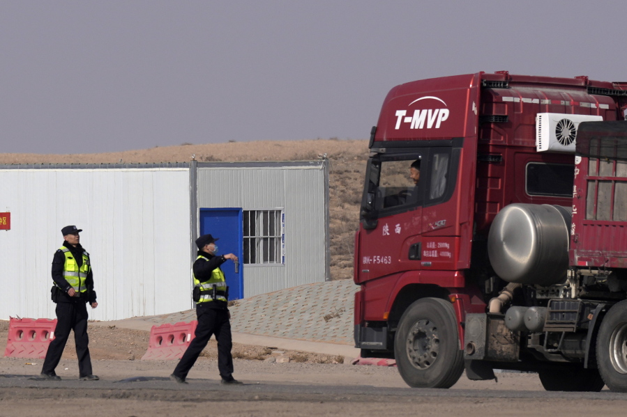 Police officers talk to a truck driver stopped at a checkpoint along a road in Qingtongxia on northern China's Ningxia Hui Autonomous Region leading to the site of a collapsed open pit mine in Alxa League in northern China's Inner Mongolia Autonomous Region, Friday, Feb. 24, 2023. Rescuers have changed their approach to search for dozens of people missing from a coal mine collapse in northern China to avoid further landslides, state broadcaster CCTV reported Friday.