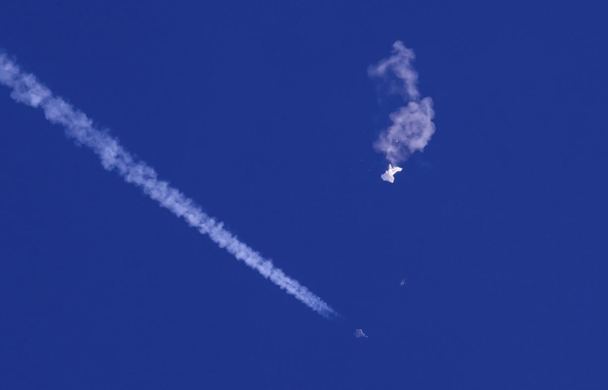 In this photo provided by Chad Fish, the remnants of a large balloon drift above the Atlantic Ocean, just off the coast of South Carolina, with a fighter jet and its contrail seen below it, Feb. 4, 2023. China said Tuesday, Feb. 7, 2023, it will "resolutely safeguard its legitimate rights and interests" over the shooting down of a suspected Chinese spy balloon by the United States, as relations between the two countries deteriorate further.