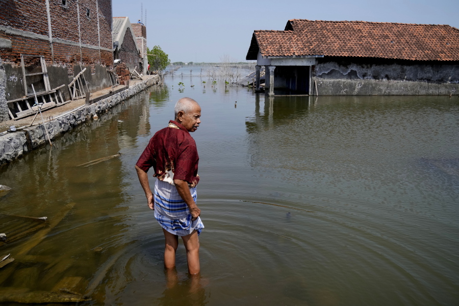 FILE - Sukarman walks on a flooded pathway outside his house in Timbulsloko, Central Java, Indonesia, July 30, 2022. Secretary-General Antonio Guterres warned Tuesday, Feb. 14, 2023, that even if global warming is "miraculously" limited to 1.5 degrees Celsius (2.7 degrees Fahrenheit), there will still be a sizable sea level rise.