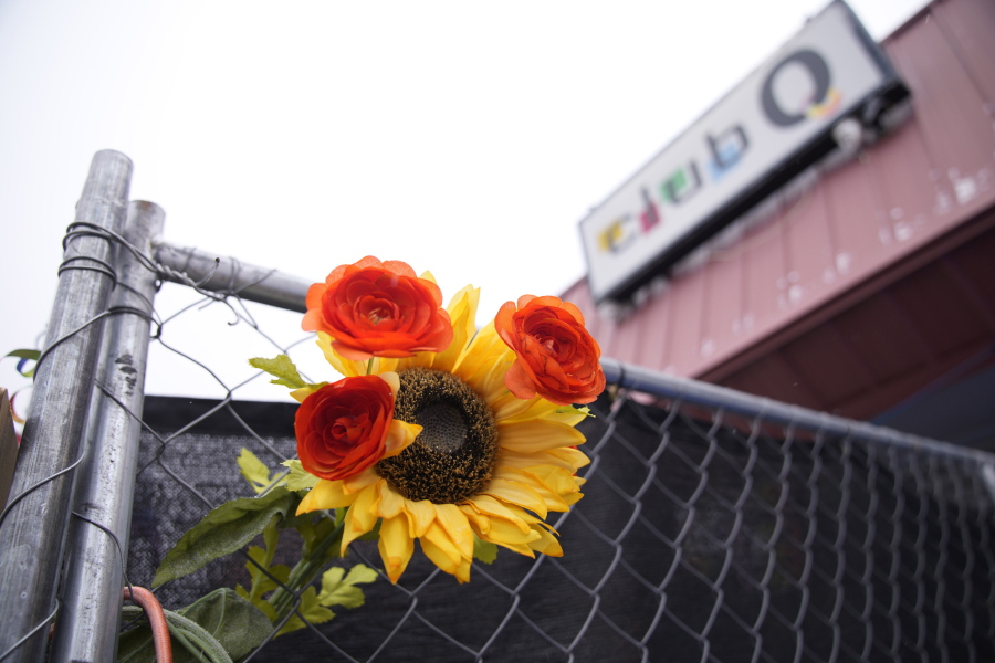 A tribute is placed in a fence of Club Q, which was the site of a mass shooting in November 2022, Wednesday, Feb. 22, 2023, in Colorado Springs, Colo. A Navy sailor grabbed the barrel of a gunman's rifle and an Army veteran rushed in to help as they ended the deadly mass shooting at the gay nightclub in November, a police detective testified Wednesday.