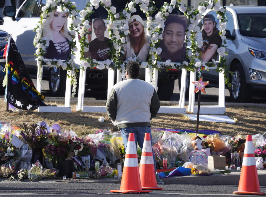 FILE - A person pauses to pay respects as portraits of the victims of a mass shooting at a gay nightclub are displayed at a makeshift memorial Nov. 22, 2022, near the scene in Colorado Springs, Colo. A court hearing is scheduled to start Wednesday, Feb. 22 ,for the 22-year-old suspect in the shooting.
