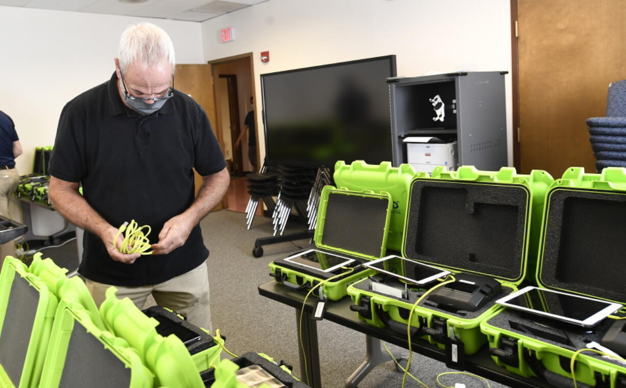 FILE - Mark Splonskowski assembles electronic poll book kits that voters will uses to sign in at polling locations at the Albany County Board of Elections building, Oct. 14, 2020, in Albany, N.Y. Attempts to develop the first-ever national standards for electronic voter rolls, the source of problems and hacking concerns in previous elections, may not be ready or available for wide use in time for the 2024 presidential election, concerning election experts.