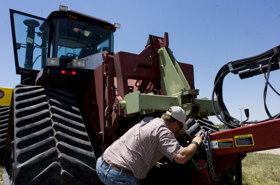 FILE - Farmer Nathan Weathers configures a high-power, high-tech quad-track tractor near his farm in Yuma, Colo, June 30, 2008. Lawmakers in Colorado and 10 other states have introduced bills that would force farming equipment manufacturers to provide the tools, software, parts and manuals needed for farmers to do their own repairs. The bills are a response to farmers unable to repair their own tractors and combines, forcing them to wait sometimes days and paying steep labor costs.