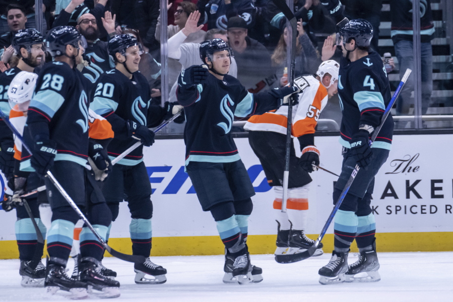Seattle Kraken forward Yanni Gourde, center, is congratulated by defenseman Justin Schultz (4), defenseman Carson Soucy (28) and forward Eeli Tolvanen (20) after scoring a goal during the first period of an NHL hockey game against the Philadelphia Flyers, Thursday, Feb. 16, 2023, in Seattle.