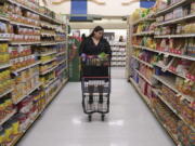 Jaqueline Benitez pushes her cart down an aisle as she shops for groceries at a supermarket in Bellflower, Calif., on Monday, Feb. 13, 2023. Benitez, 21, who works as a preschool teacher, depends on California's SNAP benefits to help pay for food, and starting in March she expects a significant cut, perhaps half, of the $250 in food benefits she has received since 2020.