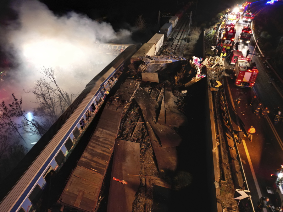 Smoke rises from trains as firefighters and rescuers operate after a collision near Larissa city, Greece, early Wednesday, March 1, 2023. The collision between a freight and passenger train occurred near Tempe, some 380 kilometers (235 miles) north of Athens, and resulted in the derailment of several train cars.
