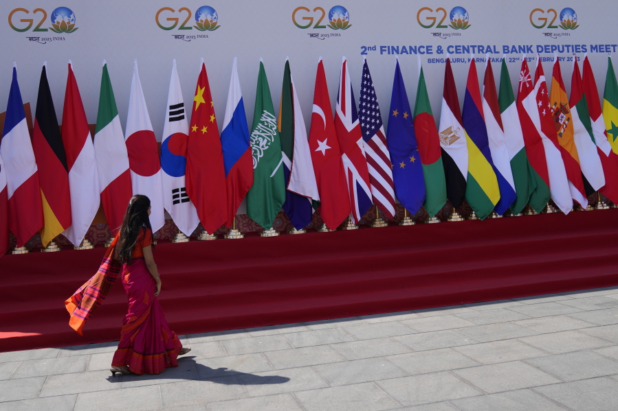 A delegate walks past a display of flags of participating countries at the venue of G-20 financial conclave on the outskirts of Bengaluru, India, Wednesday, Feb. 22, 2023. Top financial leaders from the Group of 20 leading economies are gathering in the south Indian technology hub of Bengaluru to tackle challenges to global growth and stability. India is hosting the G-20 financial conclave for the first time in 20 years.