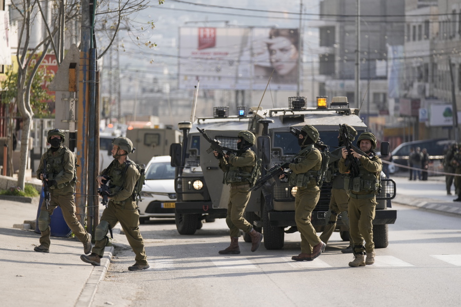Israeli soldiers take up positions at the scene of a Palestinian shooting attack at the Hawara checkpoint, near the West Bank city of Nablus, Sunday, Feb. 26, 2023.