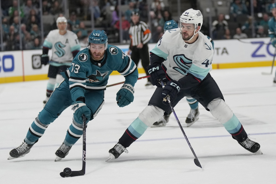 San Jose Sharks center Noah Gregor, left, reaches for the puck next to Seattle Kraken defenseman Jaycob Megna during the second period of an NHL hockey game in San Jose, Calif., Monday, Feb. 20, 2023.