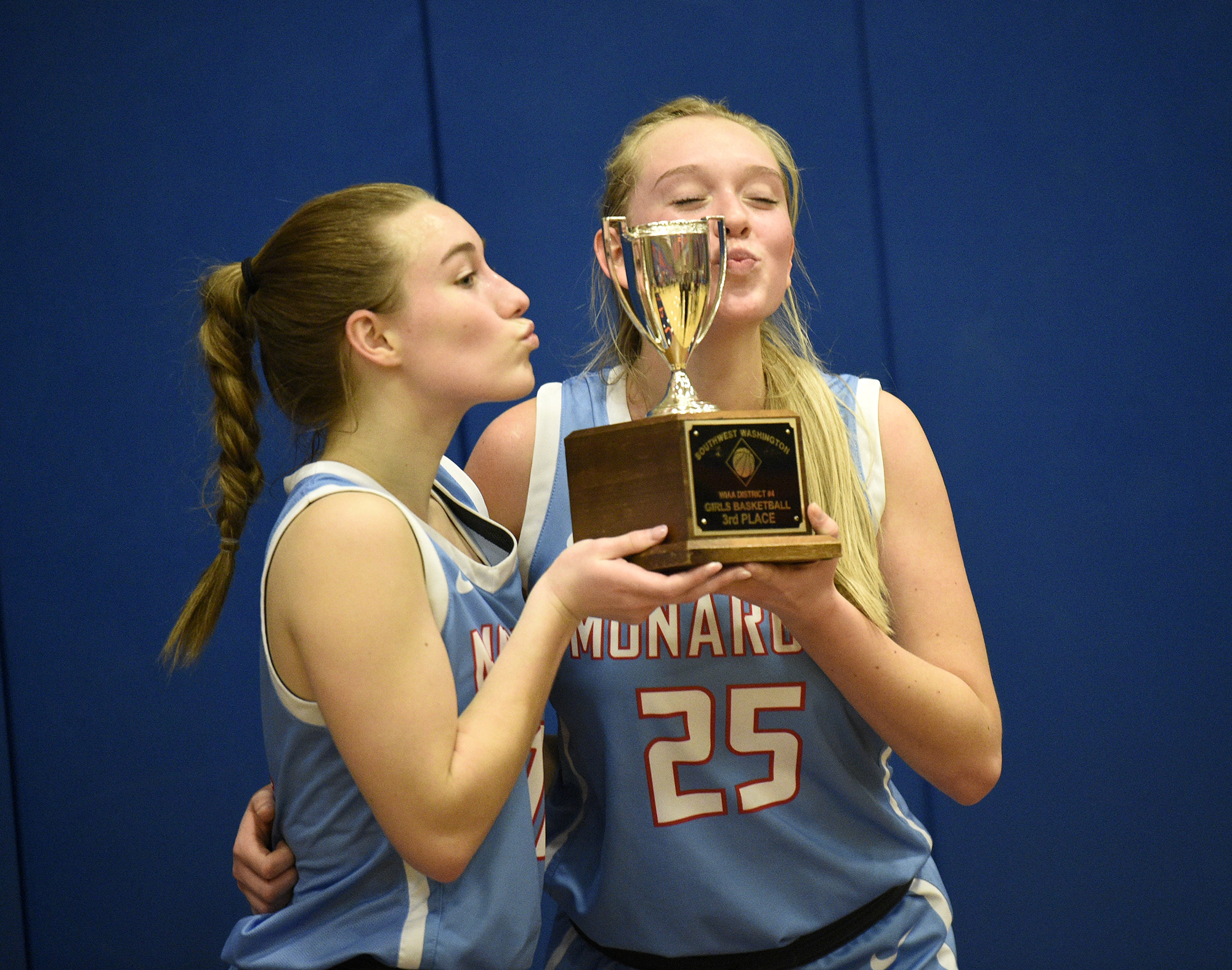 Mark Morris seniors Brooklyn Schlect and Isabella Merzoian (25) pose with the third-place trophy after winning the 2A district girls basketball tournament winner-to-state game at Ridgefield High School on Wednesday, Feb. 15, 2023.