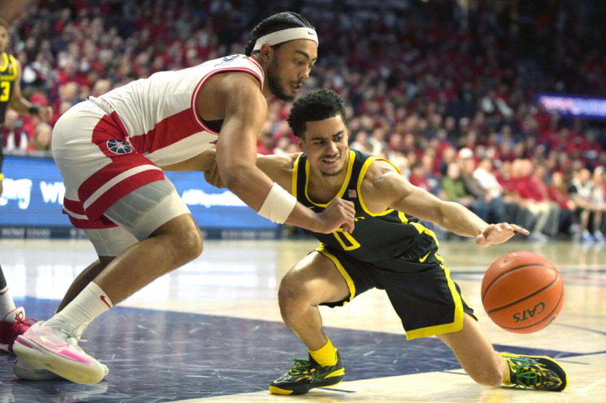 Arizona guard Kylan Boswell, left, and Oregon guard Will Richardson (0) reach for the ball during the first half of an NCAA college basketball game, Thursday, Feb. 2, 2023, in Tucson, Ariz.