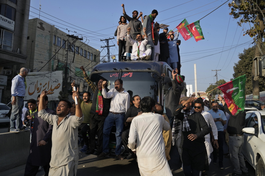 Supporters of Pakistan's former prime minister Imran Khan's 'Pakistan Tehreek-e-Insaf' party climb on a police van and chat ant government slogans during a rally, in Lahore, Pakistan, Wednesday, Feb. 22, 2023. Hundreds of supporters of Pakistan's former prime minister on Wednesday defied a ban on rallies in a commercial area of the city of Lahore, taunting police and asking to be arrested en masse. (AP Photo/K.M.