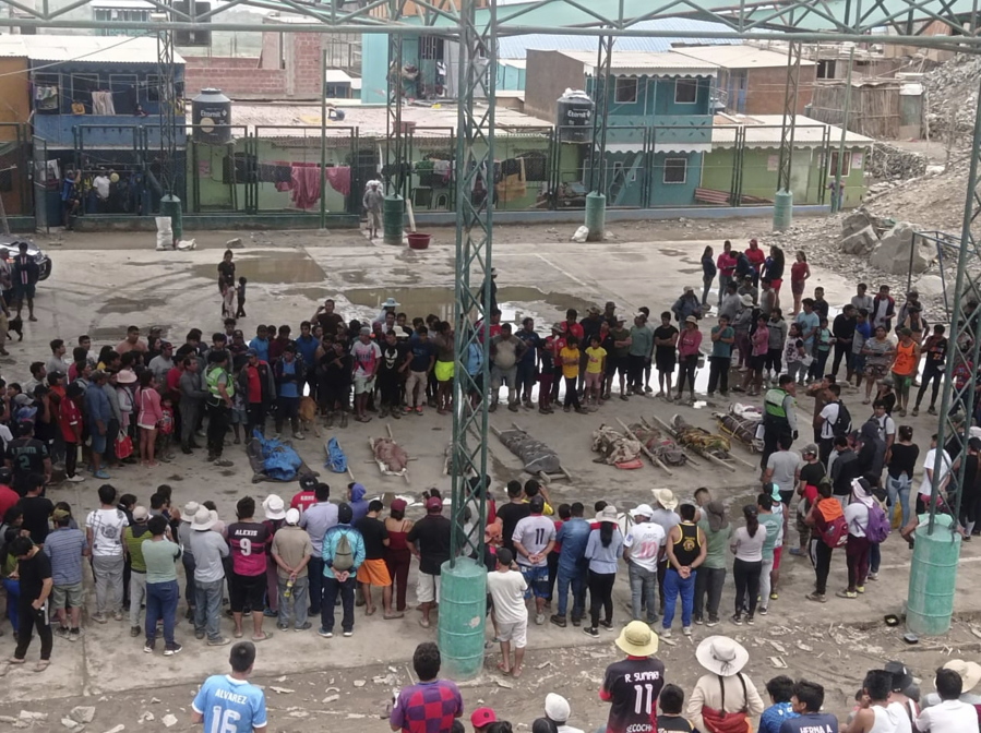 Residents stand around the bodies of persons who perished in recent landslides in Camana, Peru, Monday, Feb. 6, 2023. According to a preliminary report issued by Civil Defense, more than 30 people died as a consequence of non-stop heavy rains and landslides.