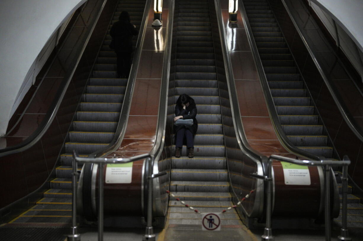 A woman sits in a subway station being used as a bomb shelter during an air siren in Kyiv, Ukraine, Friday, Feb. 3, 2023.