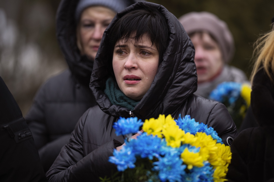 A woman cries during a memorial service to mark the one-year anniversary of the start of the Russia Ukraine war, in a cemetery in Bucha, Ukraine, Friday, Feb. 24, 2023.