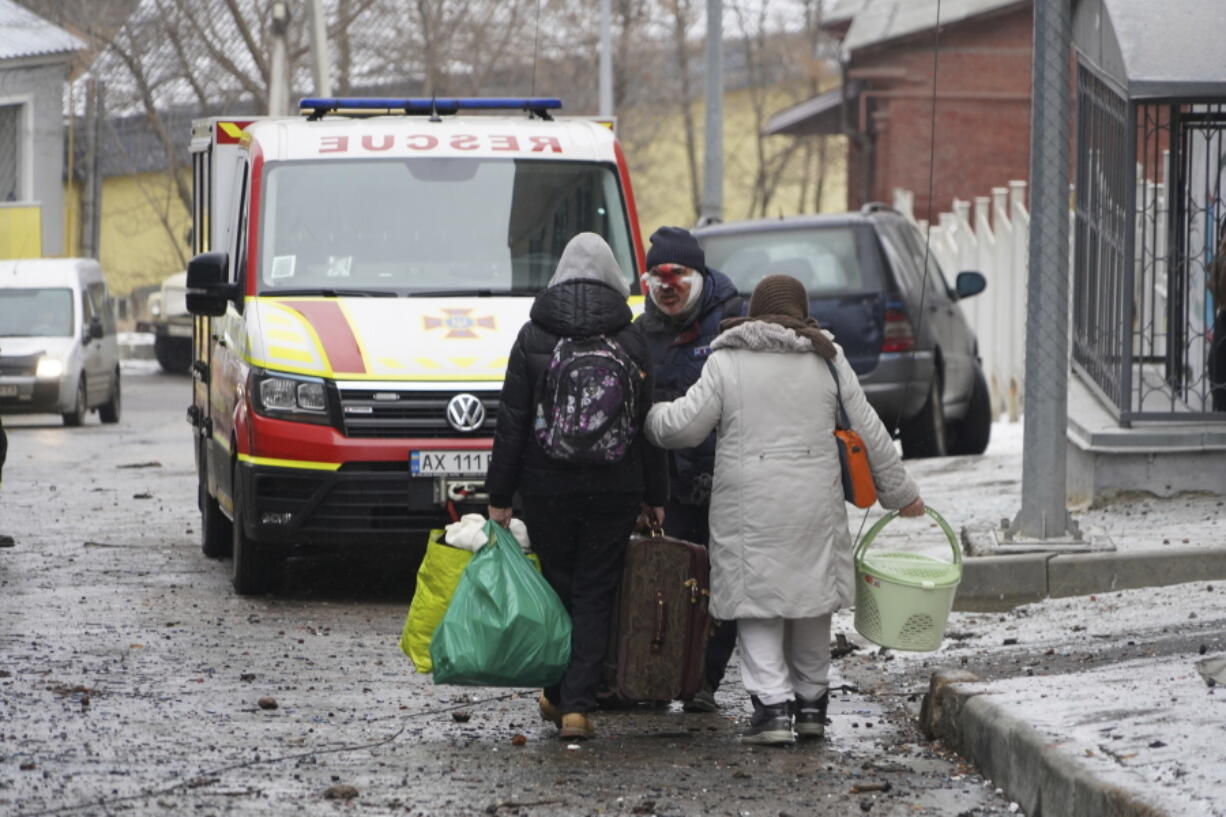 An injured man evacuates with family members from a residential building which was hit by a Russian rocket at the city center of Kharkiv, Ukraine, Sunday, Feb. 5, 2023.