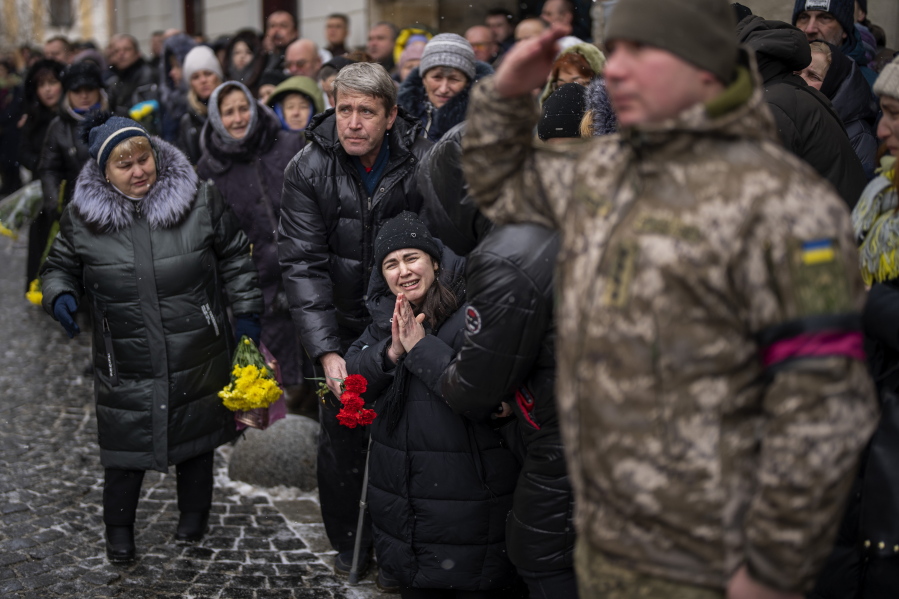 Anastasia, center, cries as soldiers carry the coffin of her brother Oleg Kunynets, a Ukrainian military servicemen who were killed in the east of the country, during his funeral in Lviv, Ukraine, Tuesday, Feb 7, 2023.