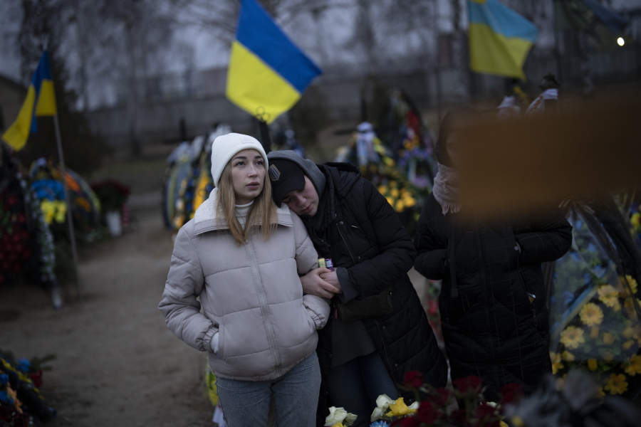 Anastasiia Okhrimenko, left, and Anna Korostenska visit the cemetery together in Bucha, Ukraine, where their partners are buried, Monday, Jan. 23, 2023. As the conflict that killed their loved ones still rages on, Anna, Anastasiia and her brother, Vadym wrestle with a question that all of war-torn Ukraine must grapple with: After loss, what comes next?