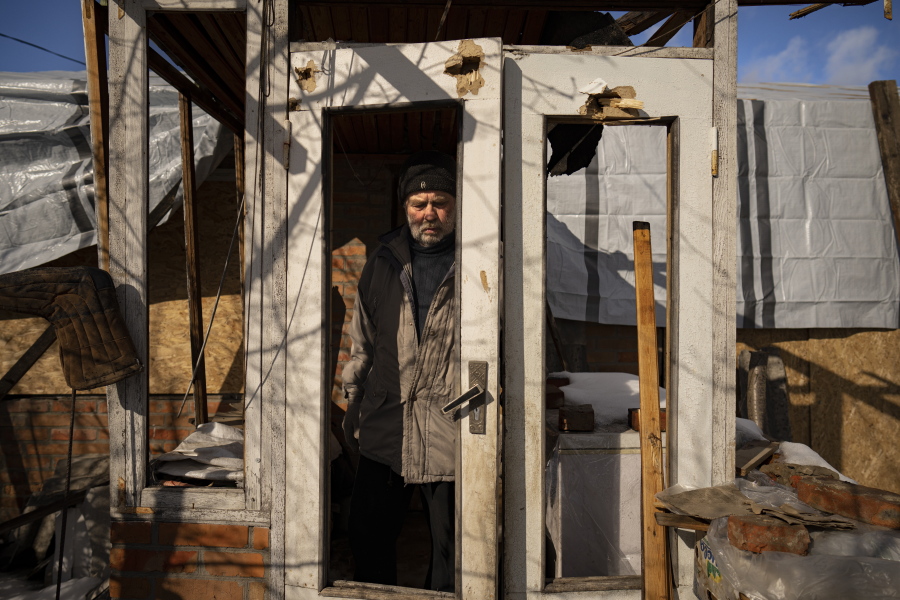 Oleksandr Luzhan, whose mother's house was struck twice, exits the shrapnel riddled building, in Kupiansk, Ukraine, Monday, Feb. 20, 2023. Luzhan picked up insulation kits, containing wooden boards and other items, supplied by an aid group called HEKS/EPER Swiss Church Aid and said to increase indoor temperatures in battered homes by at least 5 degrees to seal his mother's house.