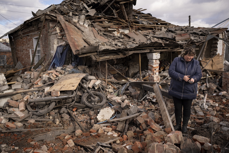 FILE - A woman holds a piece of shrapnel standing in the rubble of a house where Ukrainian servicemen were sheltering which destroyed by a Russian S-300 rocket strike, in Kupiansk, Ukraine, Monday, Feb. 20, 2023. Grueling artillery battles have stepped up in recent weeks in the vicinity of Kupiansk, a strategic town on the eastern edge of Kharkiv province by the banks of the Oskil River as Russian attacks intensifying in a push to capture the entire industrial heartland known as the Donbas, which includes the Donetsk and the Luhansk provinces.