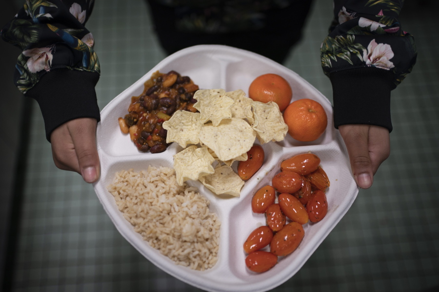 A 7th grader carries her plate which consists of three bean chili, rice, mandarins and cherry tomatoes and baked chips during her lunch break at a local public school, Saturday, Feb. 11, 2023, in the Brooklyn borough of New York. A 2010 federal law that boosted nutrition standards for school meals may have helped curb obesity among America'??s children _ even teenagers who can buy their own snacks, according to a study published Monday, Feb. 13, 2023, in the journal JAMA Pediatrics.