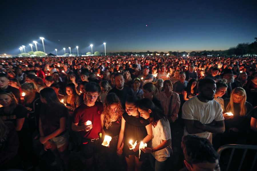 FILE - People attend a candlelight vigil for the victims of the Wednesday shooting at Marjory Stoneman Douglas High School, in Parkland, Fla., Thursday, Feb. 15, 2018. After a gunman murdered 14 students and three staff members at Parkland's Marjory Stoneman Douglas High School, their families were left with a burning question: How do we go on with our lives while honoring our loved one's memory?