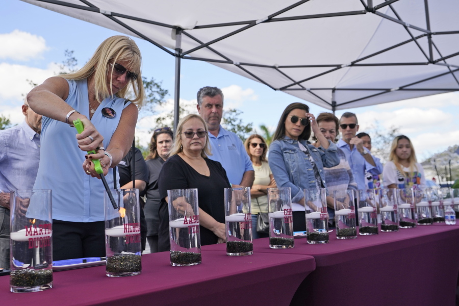 Annika Dworet, left, mother of shooting victim Nicholas Dworet, lights a candle for him, Tuesday, Feb. 14, 2023, at a ceremony in Coral Springs, Fla., honoring the lives of the 17 students and staff of Marjory Stoneman Douglas High School that were killed on Valentine's Day, 2018.
