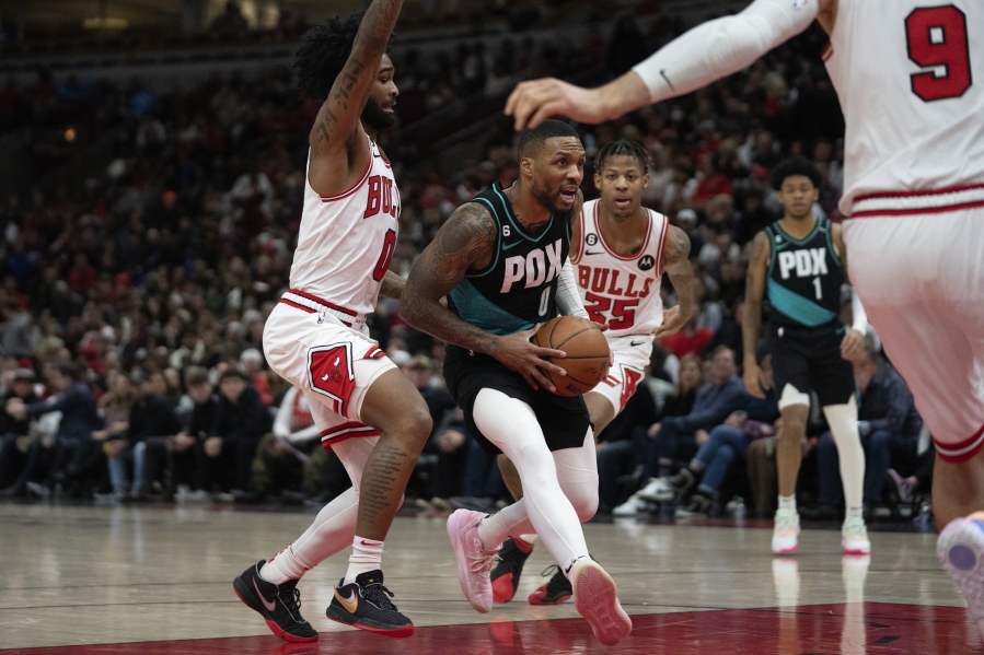 Portland Trail Blazers guard Damian Lillard, center, gets by Chicago Bulls guard Coby White, left, during the first half of an NBA basketball game Saturday, Feb. 4, 2023, in Chicago.
