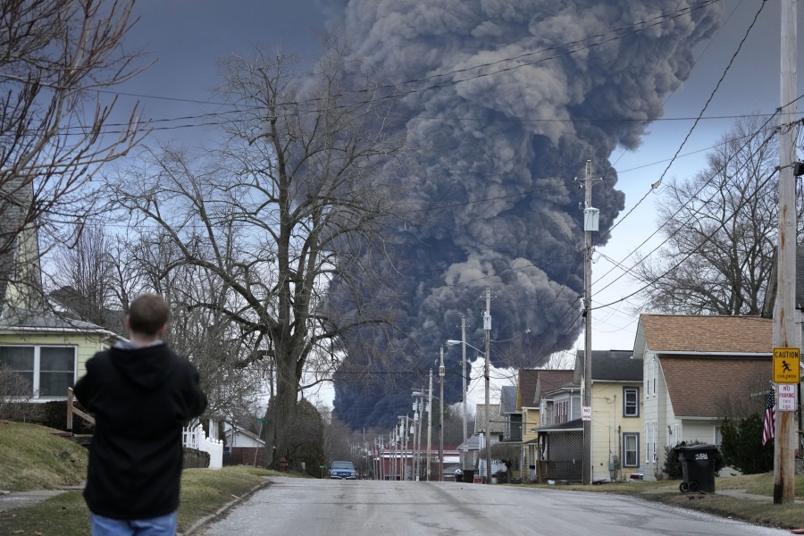 A man takes photos as a black plume rises over East Palestine, Ohio, as a result of a controlled detonation of a portion of the derailed Norfolk and Southern trains Monday, Feb. 6, 2023. (AP Photo/Gene J.