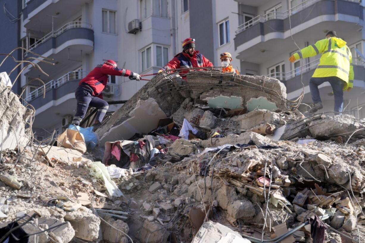 Emergency teams search for people in the rubble in a destroyed building in Adana, southern Turkey, Tuesday, Feb. 7, 2023. A powerful earthquake hit southeast Turkey and Syria early Monday, toppling hundreds of buildings and killing and injuring thousands of people.