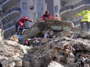 Emergency teams search for people in the rubble in a destroyed building in Adana, southern Turkey, Tuesday, Feb. 7, 2023. A powerful earthquake hit southeast Turkey and Syria early Monday, toppling hundreds of buildings and killing and injuring thousands of people.